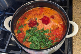 A saucepan filled with freshly boiled borscht and garnished with fresh parsley