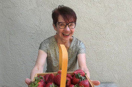 basket with strawberries in the hands of a smiling woman