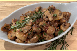 Sautéed mushrooms pieces with fresh herbs served on a white platter.