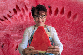 smiling woman holding a large piece of watermelon